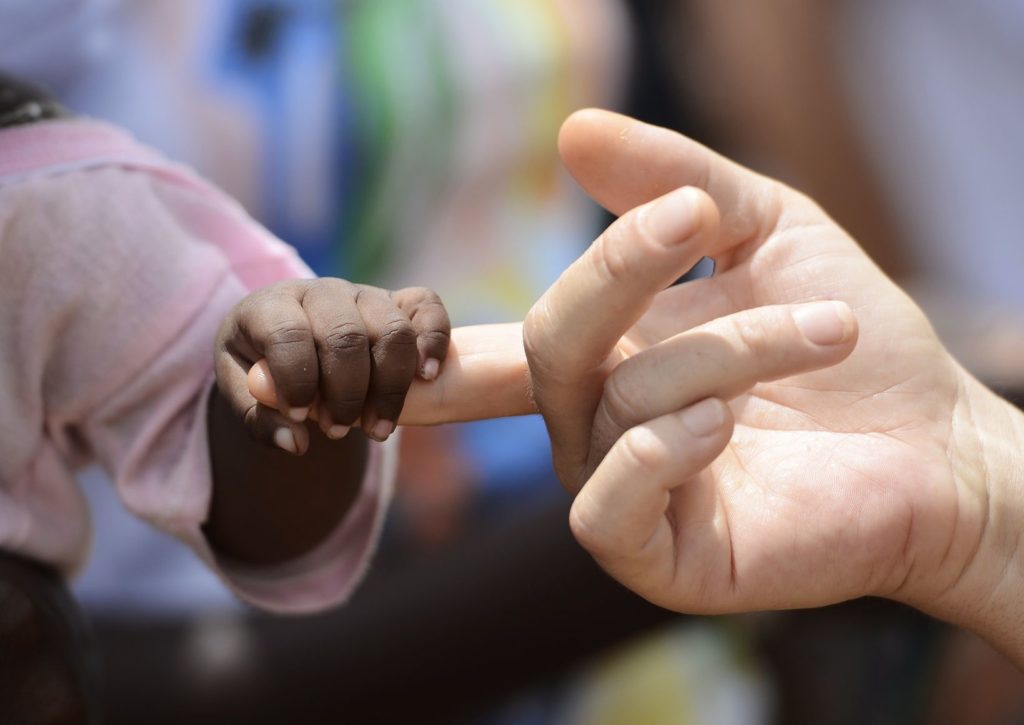 Black Baby and White woman holds hands with a little baby native African girl, in Bamako, Mali. Peace on earth symbol. A beautiful shot with lots of possible background symbols. No to Racism!