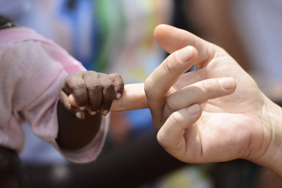 Black Baby and White woman holds hands with a little baby native African girl, in Bamako, Mali. Peace on earth symbol. A beautiful shot with lots of possible background symbols. No to Racism!